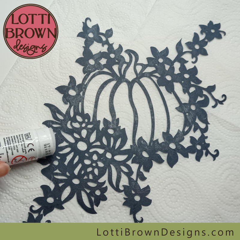 Add glue to the back of the intricate top layer with the pumpkin and flowers design
